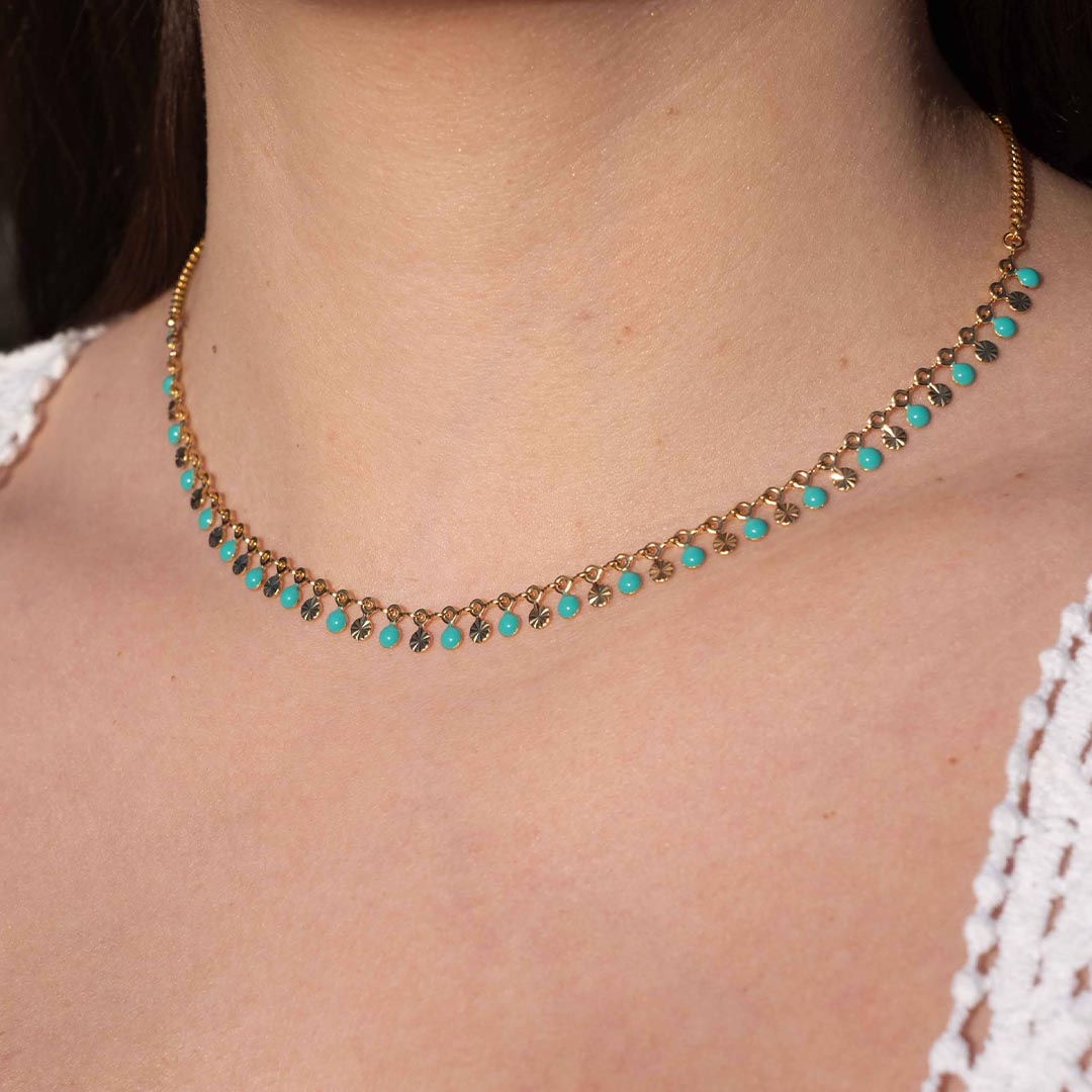 Photo d'un cou pris de près pour montrer ce magnifique bijou "ariella" en acier inoxydable qui est un collier avec une chaîne texturée et des jolies boules turquoises. Il est de couleur doré / or.