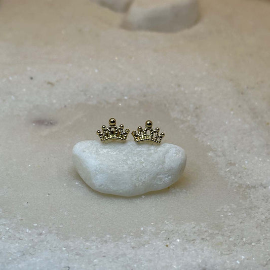 Deux très jolies boucles d'oreilles en or "cori" sont au centre de l'image, posées sur un caillou blanc. Les bijoux en acier inoxydable sont vu de face. Autour se trouve du sable blanc.